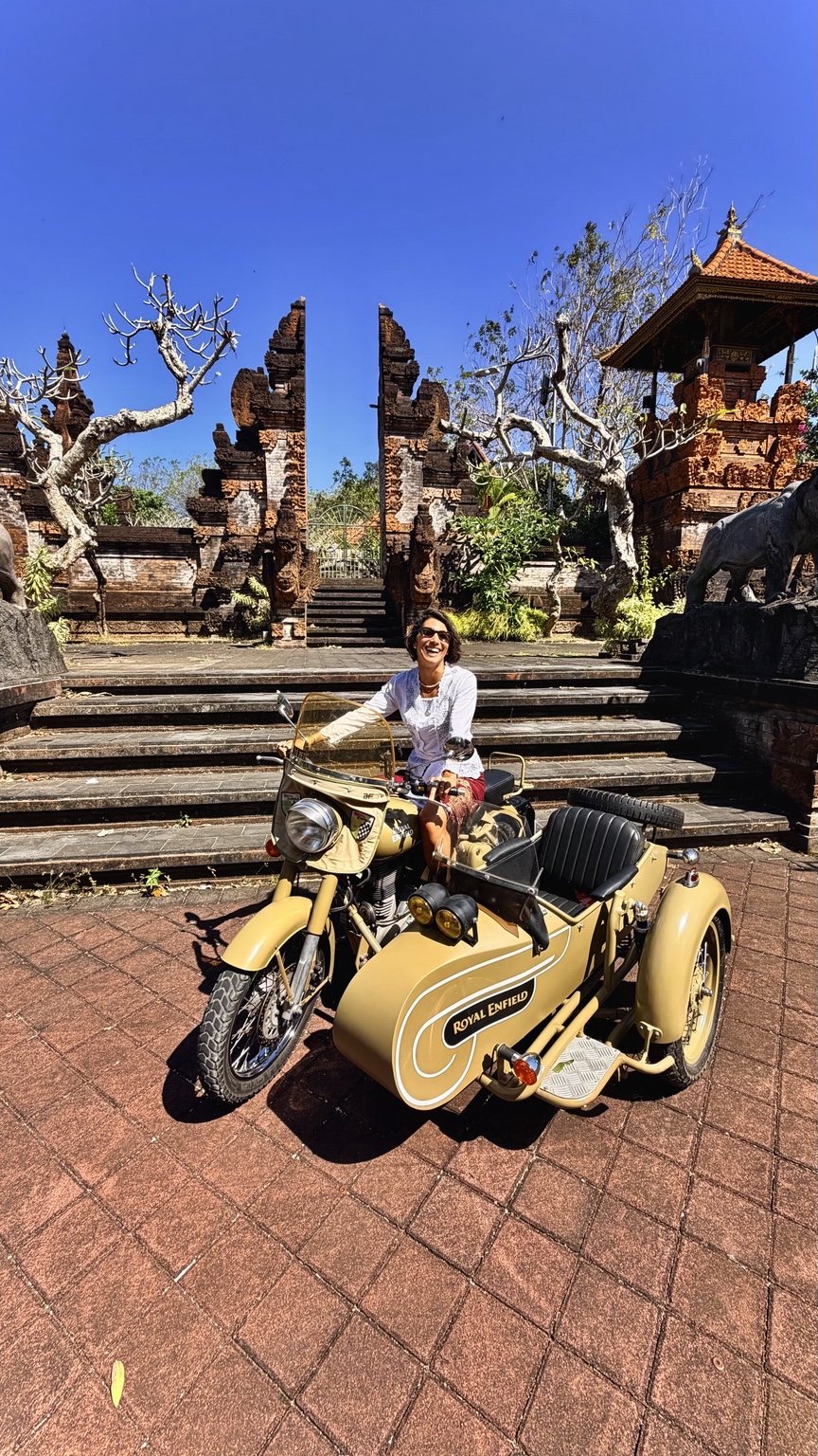Guest laughing on the Royal Enfield sidecar in front of a Balinese gate