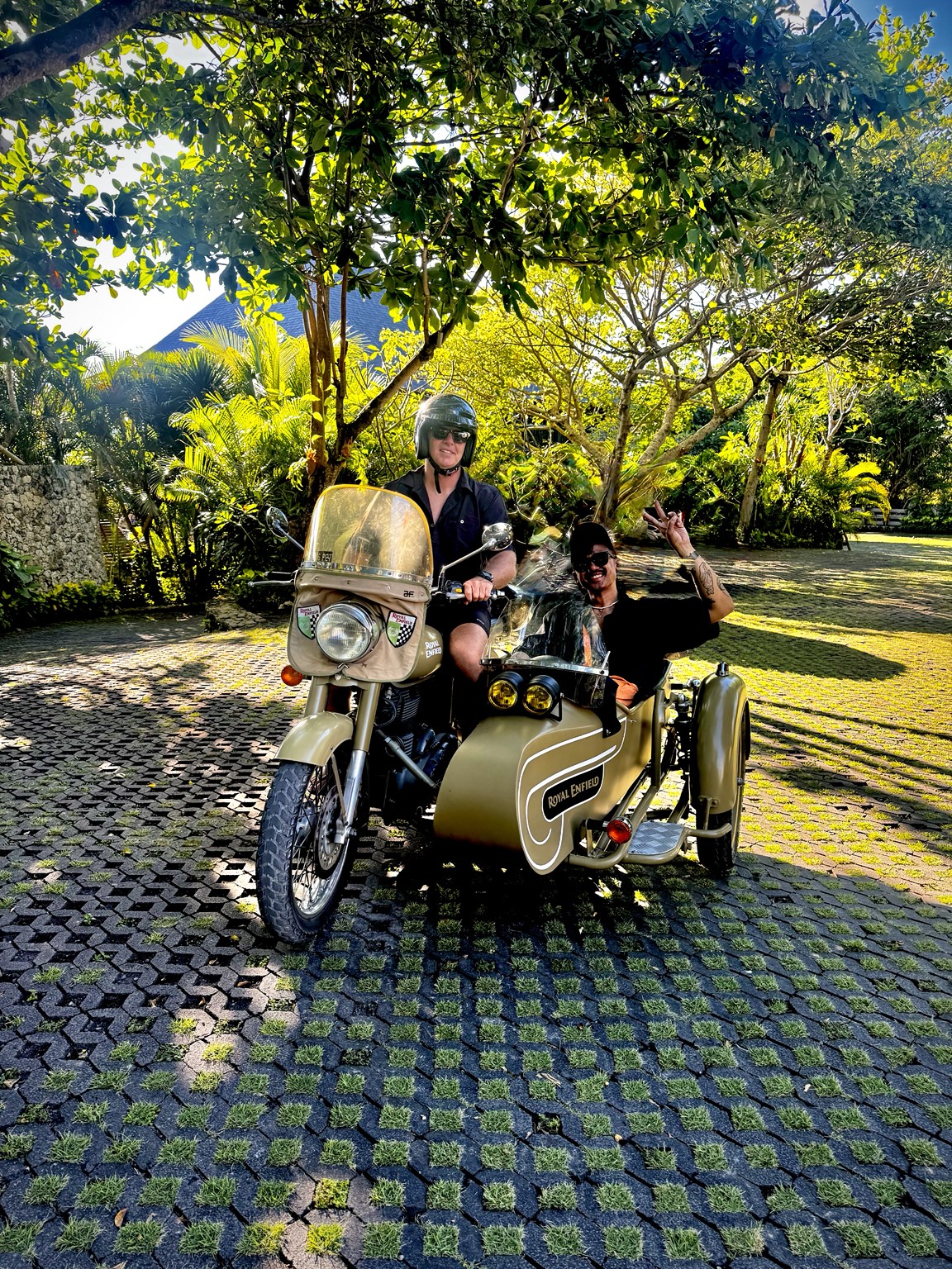 Guests enjoying the Royal Enfield sidecar beneath tropical trees in Bali