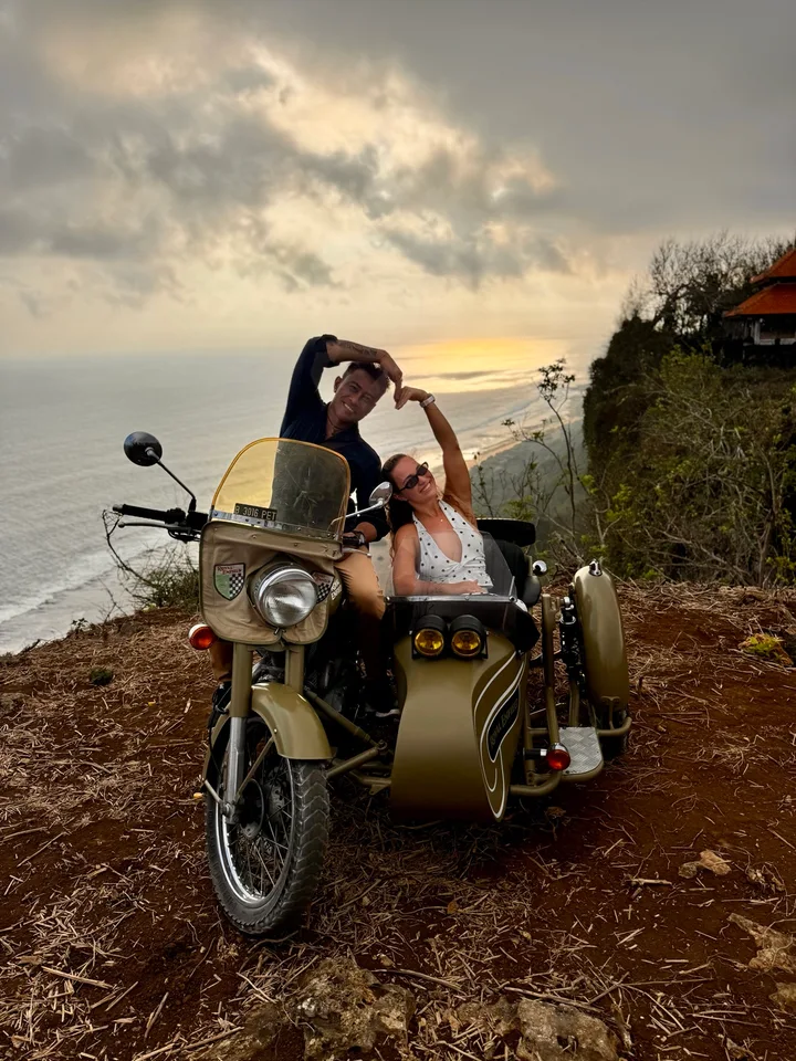 Guest on a Royal Enfield sidecar overlooking the coast at sunset