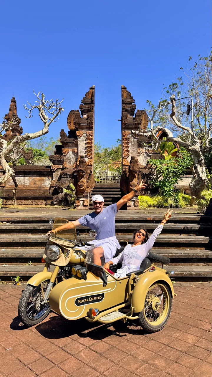 Guests posing with a sidecar in front of a traditional temple gateway